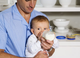 Bébé buvant le biberon dans les bras de Papa