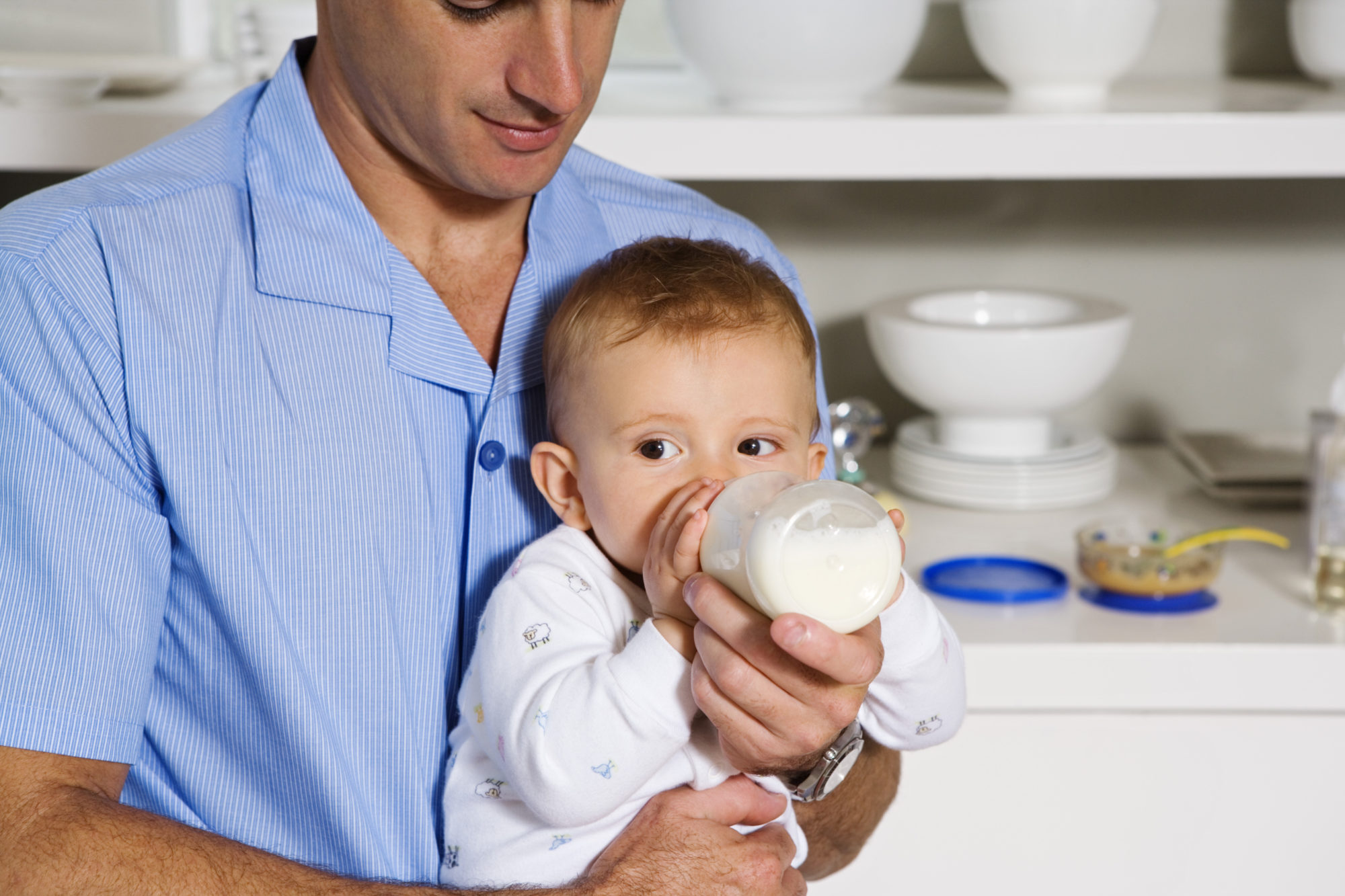 Bébé buvant le biberon dans les bras de Papa